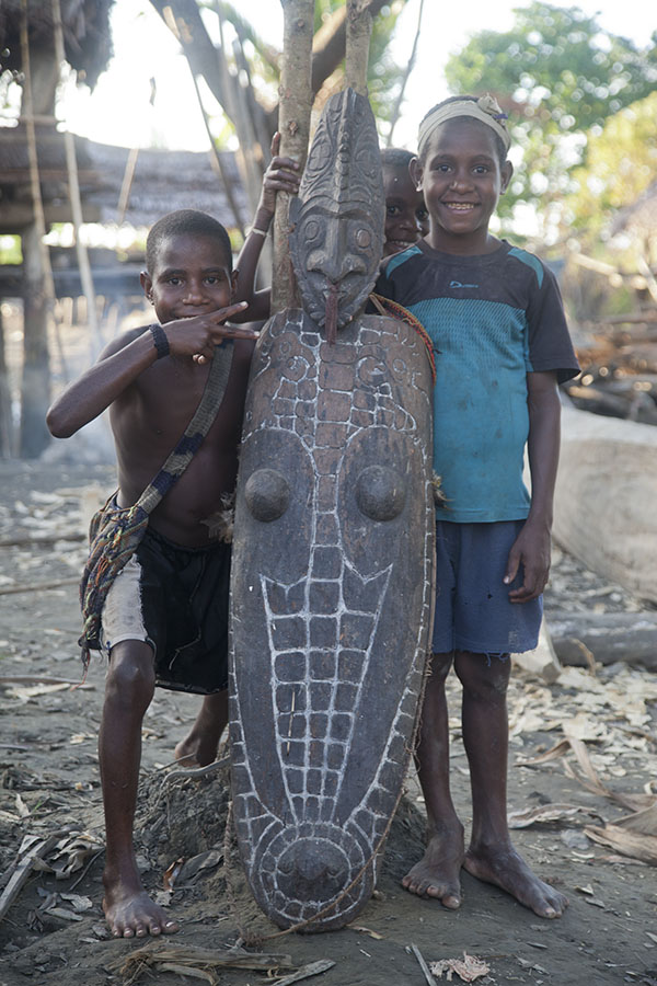 Papoea kinderen met een houtsnijwerk